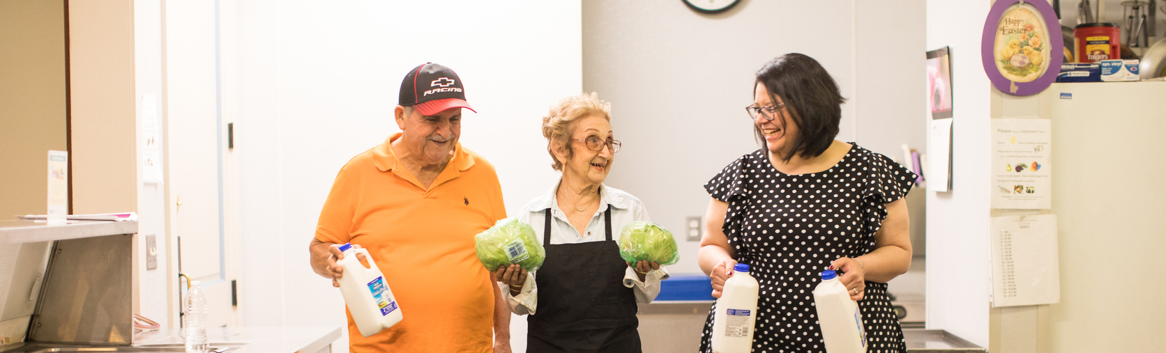 Residents Cruz Arrieda (orange shirt) and Victoria Marotta (older woman in apron) also volunteer in the kitchen. Crystal Reuwjo (Community Engagement Manager at MAUC ) also helping - seen on the right.